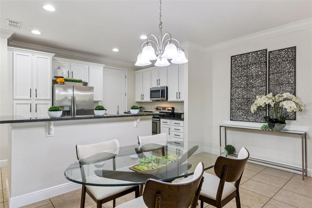 A kitchen with white cabinets and a dining area featuring a glass-topped table — 8410 KELSALL DRIVE, ORLANDO, FL