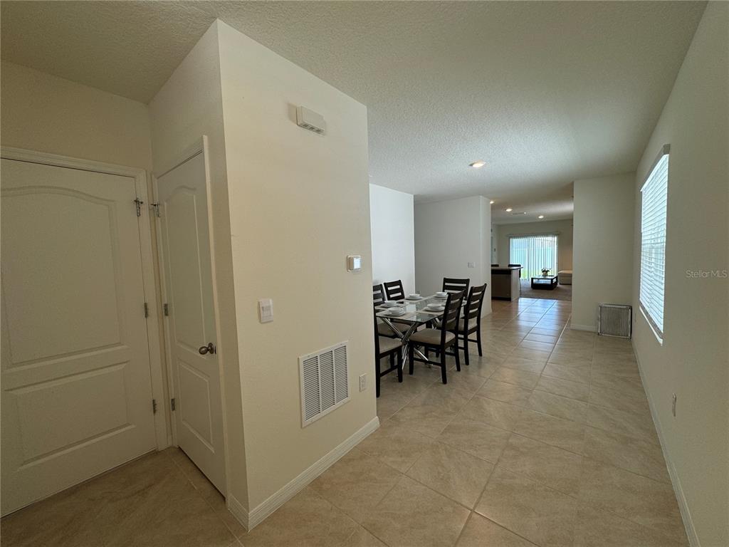 A dining area with a glass table and chairs sits adjacent to a tiled hallway — 1648 HEART BAR ROAD, KISSIMMEE, FL