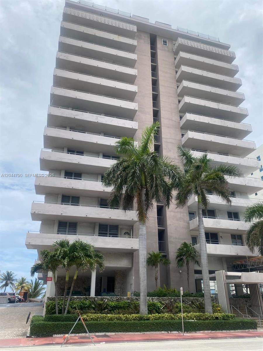 A multi-story residential building features white balconies and palm trees in the foreground — 9225 Collins Ave # 303, Surfside FL 33154, SURFSIDE, FL