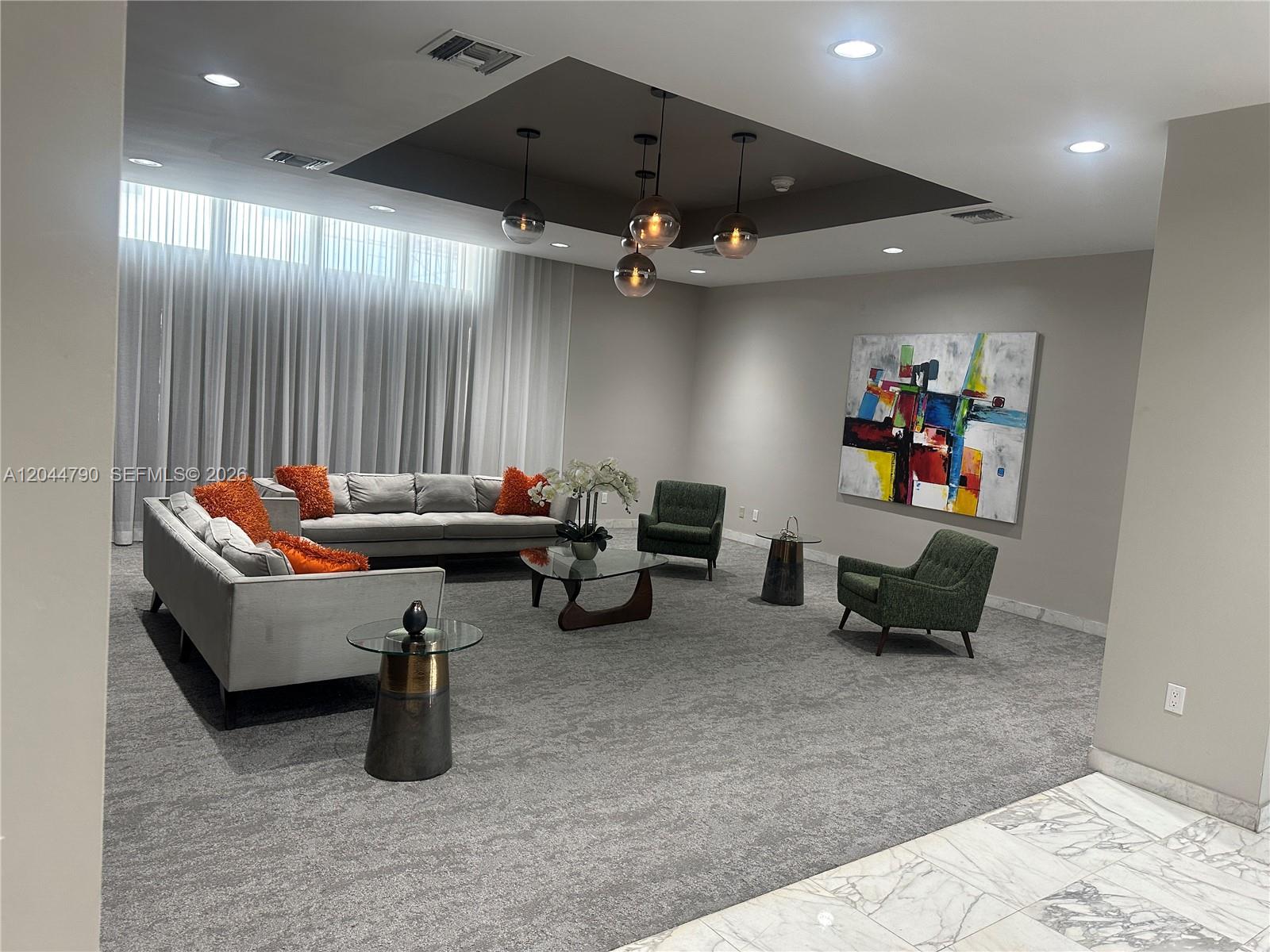 A modern living room features gray sofas, green armchairs, a glass coffee table, and pendant lighting — 9225 Collins Ave # 303, Surfside FL 33154, SURFSIDE, FL