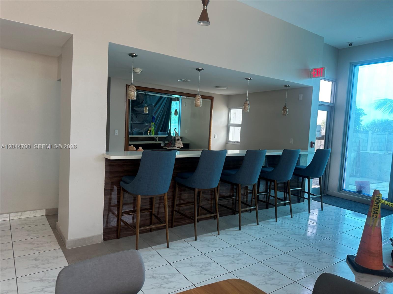 A bar area features five blue stools, a white countertop, and a large mirror — 9225 Collins Ave # 303, Surfside FL 33154, SURFSIDE, FL
