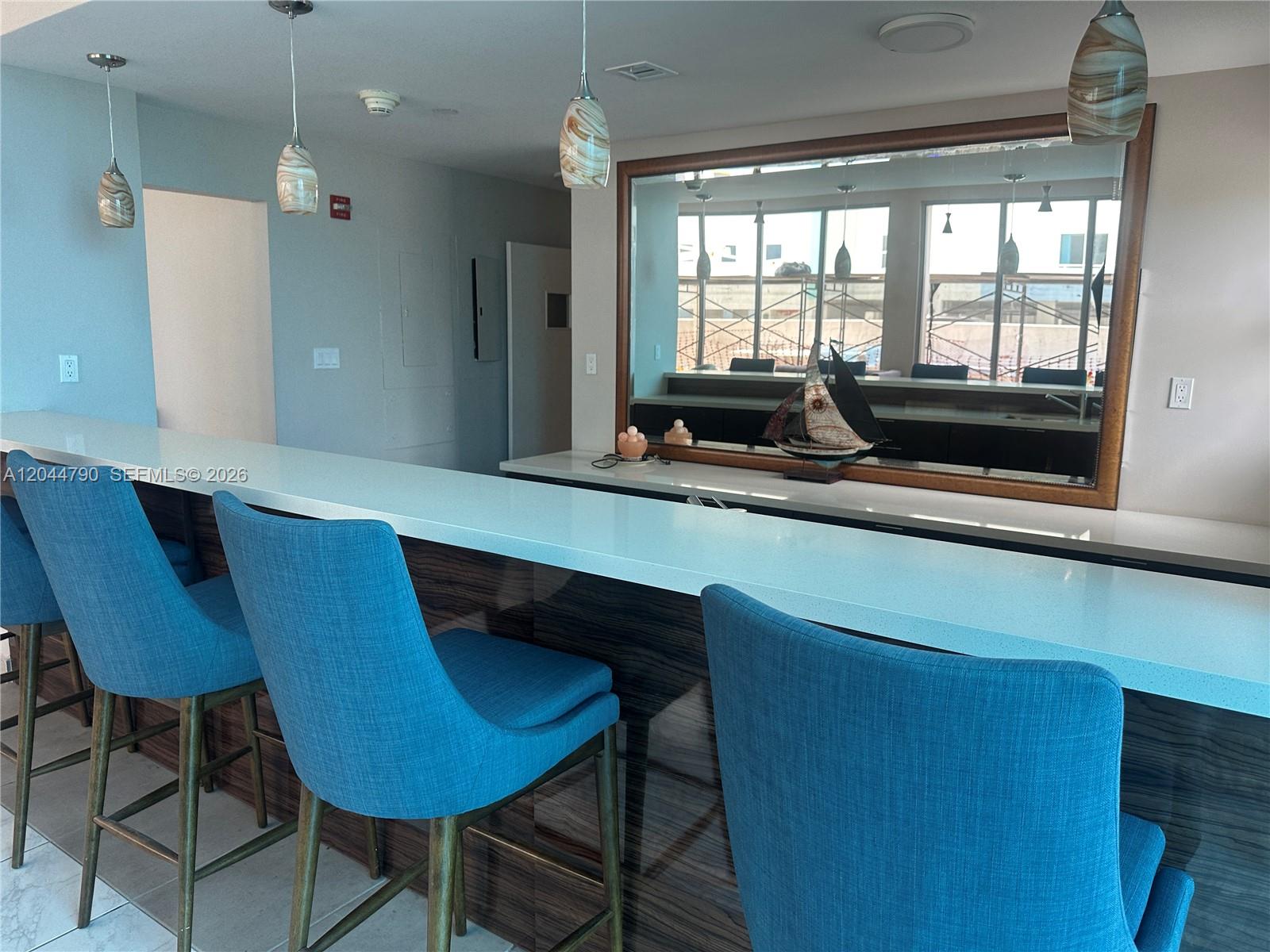 A bar area features blue upholstered stools, a white countertop, and a large wall mirror — 9225 Collins Ave # 303, Surfside FL 33154, SURFSIDE, FL