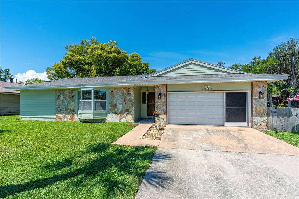 A single-story house with light green siding, stone accents, and a front-facing garage — 2916 FOXCROFT LANE, SOUTH DAYTONA, FL