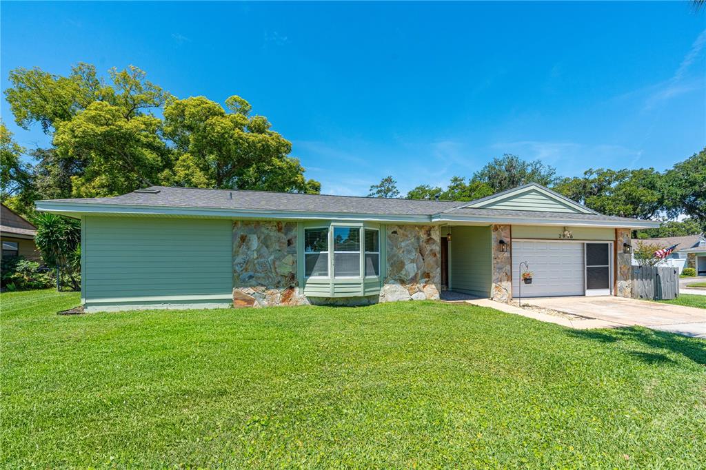 A single-story house with green siding, a stone facade, and a front-facing garage — 2916 FOXCROFT LANE, SOUTH DAYTONA, FL
