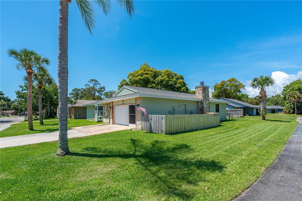 A single-story house with light green siding, a stone chimney, and a wooden privacy fence — 2916 FOXCROFT LANE, SOUTH DAYTONA, FL