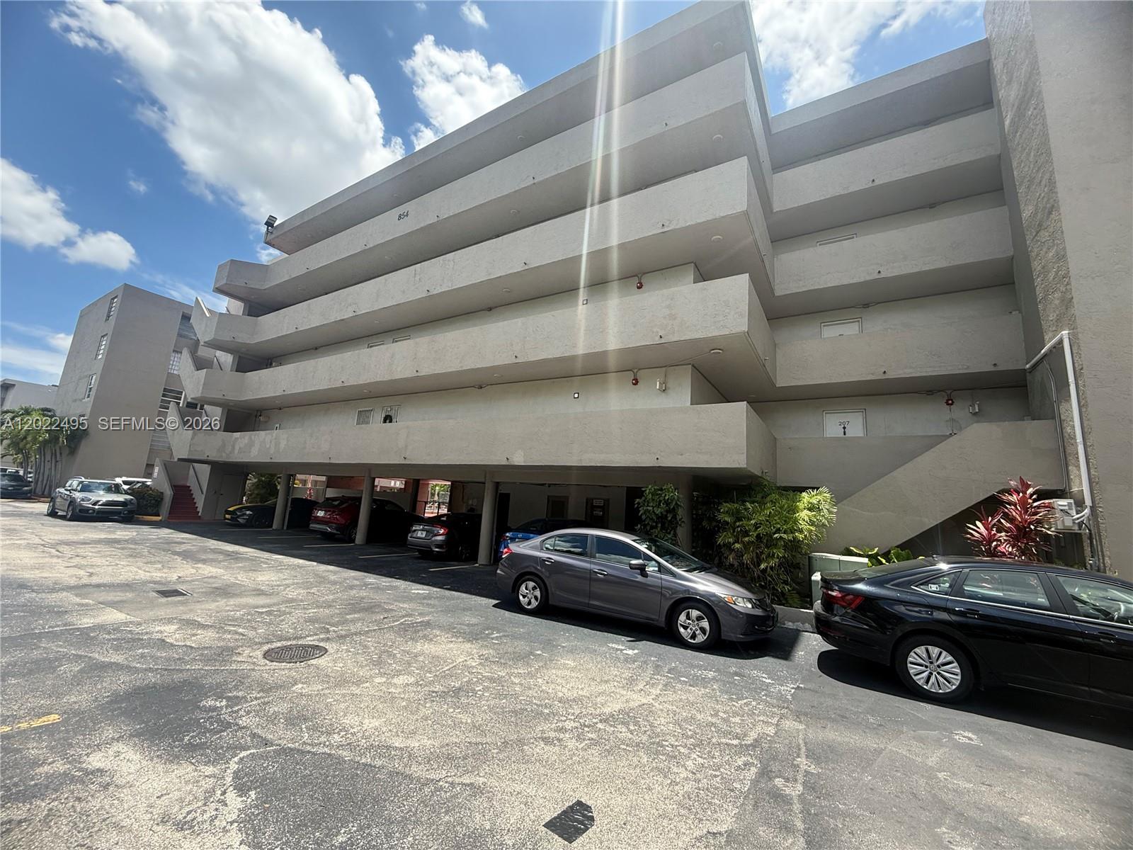 An exterior view of a multi-story apartment building with covered parking on the ground level — MIAMI, FL