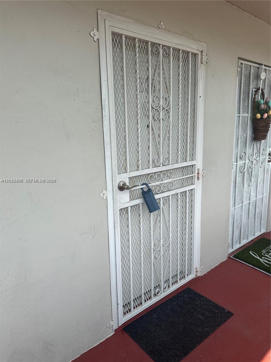 A white metal security screen door with a lockbox is installed on an exterior wall — MIAMI, FL