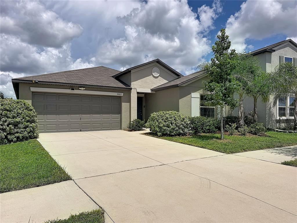 A single-story suburban house features a two-car garage, a concrete driveway, and landscaped front yard — 4465 ETERNAL PRINCE DRIVE, SUN CITY CENTER, FL