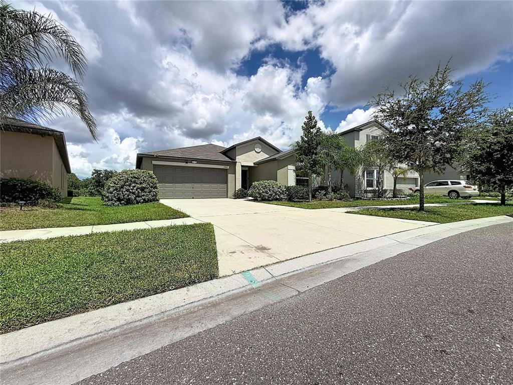 A single-story suburban house features a two-car garage, a concrete driveway, and landscaped front yard — 4465 ETERNAL PRINCE DRIVE, SUN CITY CENTER, FL