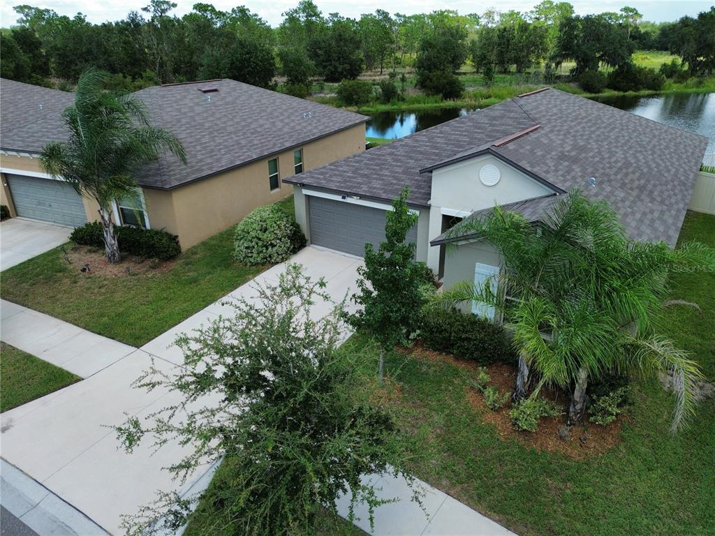 An aerial view shows two adjacent suburban houses with gray roofs, garages, and palm trees — 4465 ETERNAL PRINCE DRIVE, SUN CITY CENTER, FL