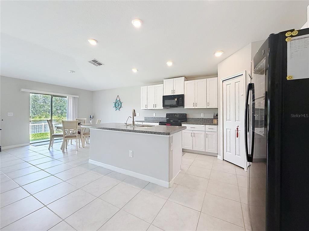 A kitchen with white cabinets, granite countertops, and an island overlooks a dining area — 4465 ETERNAL PRINCE DRIVE, SUN CITY CENTER, FL