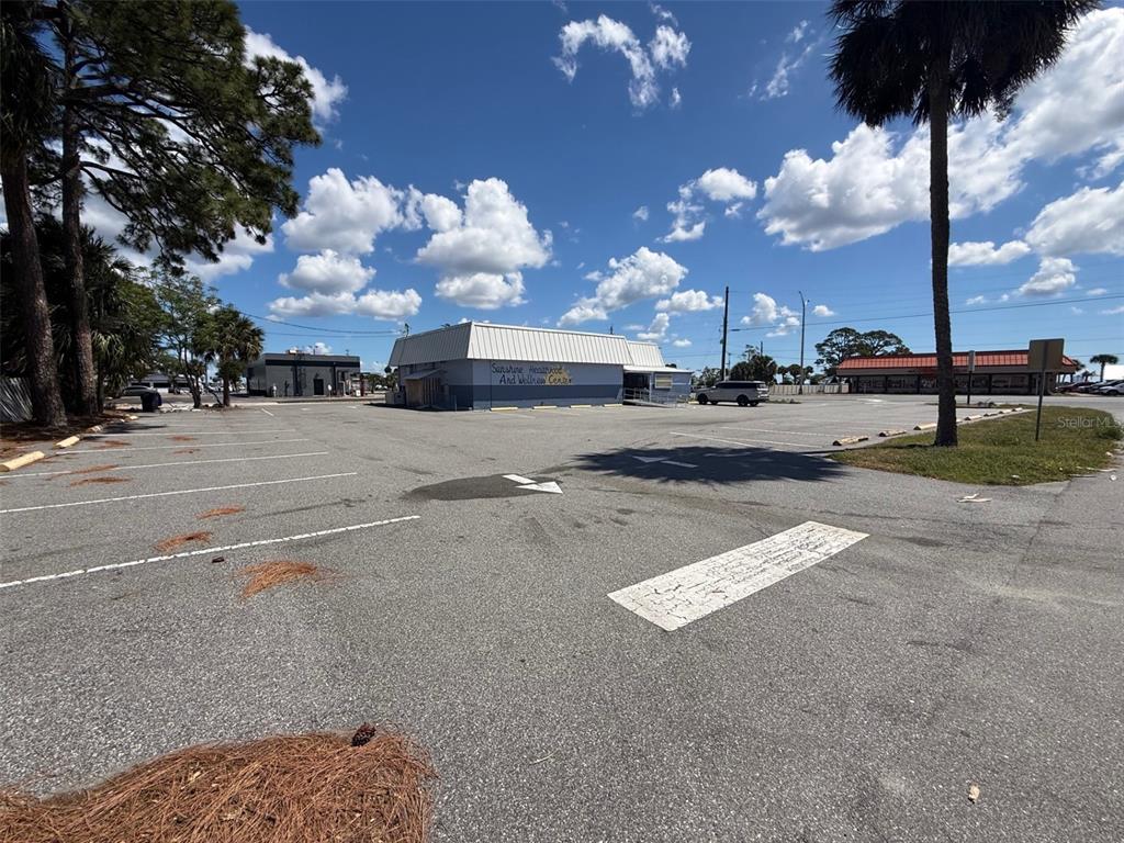 A large, empty asphalt parking lot sits in front of a single-story commercial building — 2916 S WASHINGTON AVENUE, TITUSVILLE, FL
