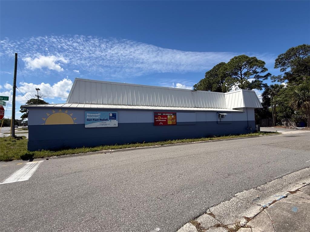 A low-slung commercial building with a white metal roof sits beside an asphalt road — 2916 S WASHINGTON AVENUE, TITUSVILLE, FL