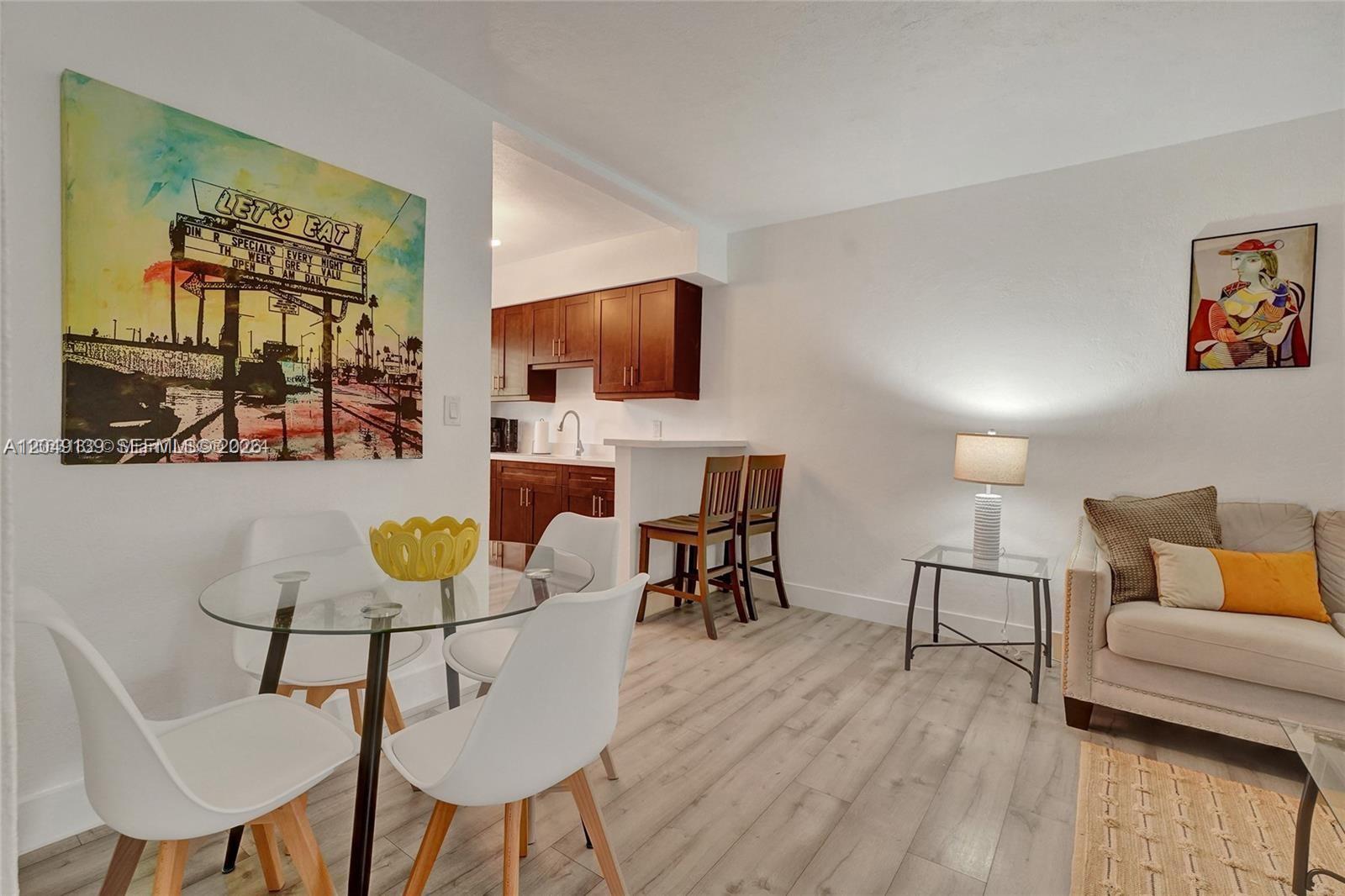 A dining area with a glass table and chairs sits adjacent to a small kitchen — 361 NW 103rd St, Miami FL 33150, MIAMI, FL