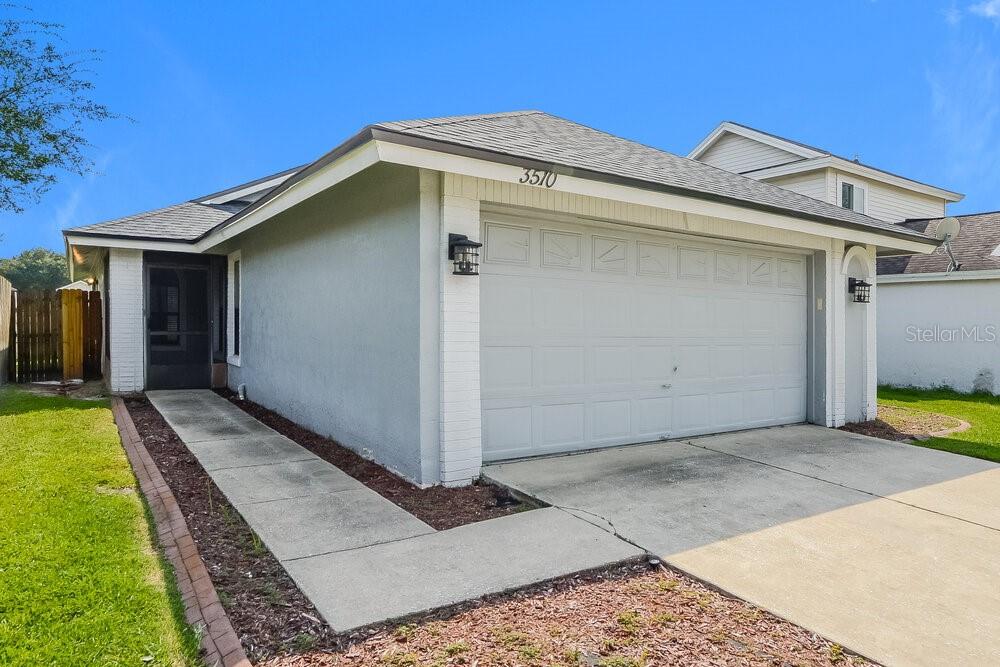 A single-story house features a light gray exterior, a two-car garage, and a concrete walkway — 3510 BUFFAM PLACE, CASSELBERRY, FL