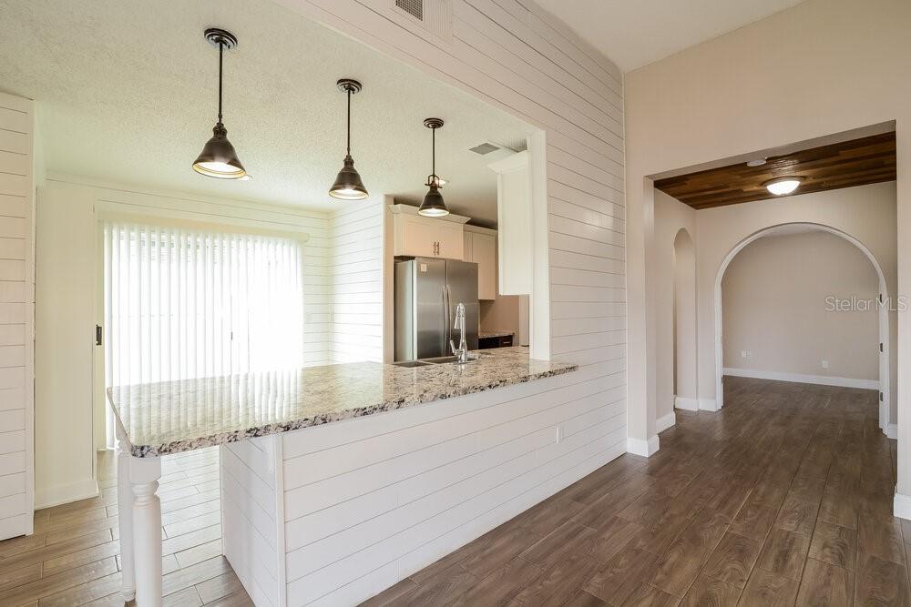 A kitchen with a granite breakfast bar, pendant lighting, and white shiplap walls — 3510 BUFFAM PLACE, CASSELBERRY, FL