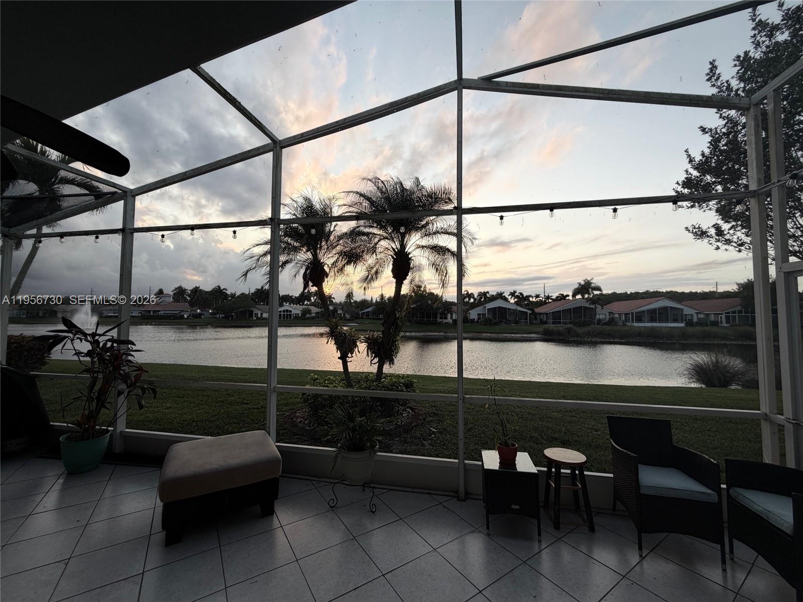 A screened-in patio overlooks a lake with palm trees and houses in the distance — 10390 E Utopia Cir E # 10390, Boynton Beach FL 33437, BOYNTON BEACH, FL
