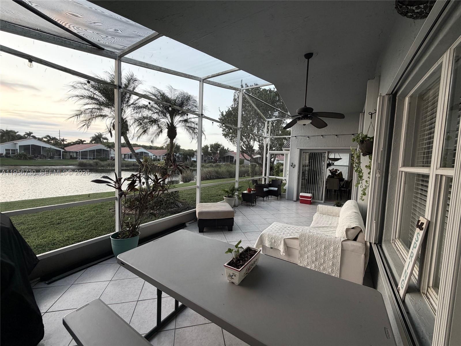 A screened-in patio features tile flooring, a ceiling fan, outdoor furniture, and a lake view — 10390 E Utopia Cir E # 10390, Boynton Beach FL 33437, BOYNTON BEACH, FL
