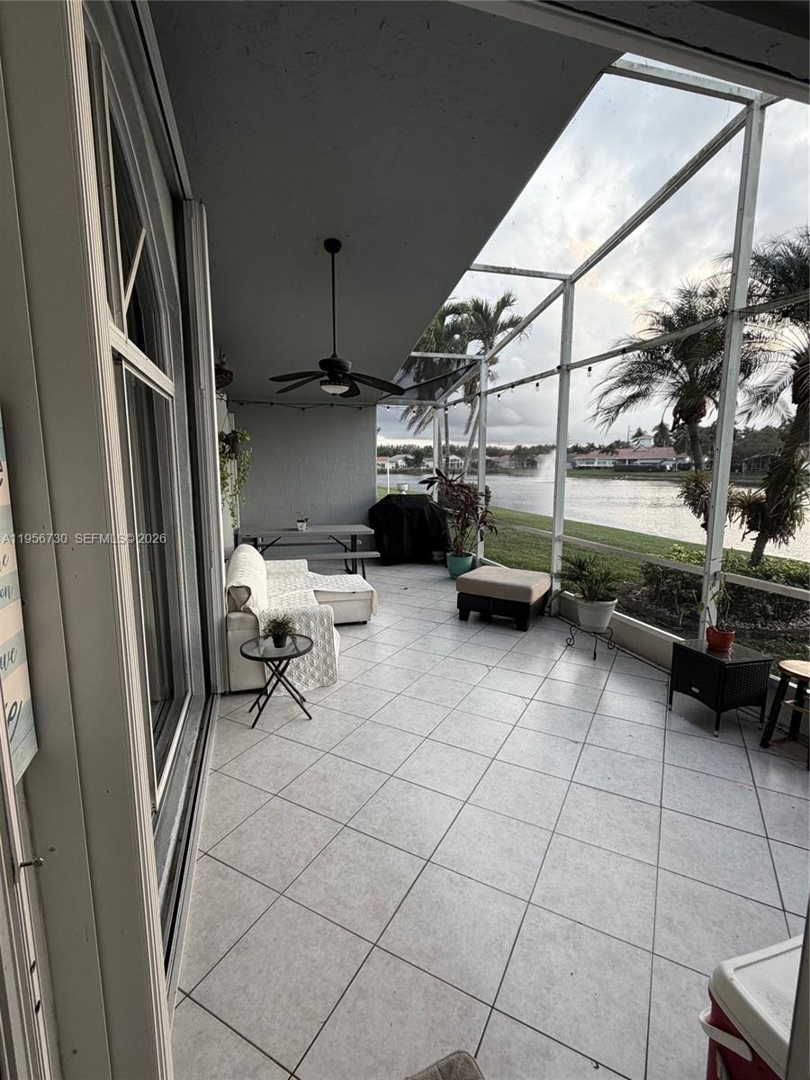 A covered patio with tile flooring features a seating area and a screened-in lake view — 10390 E Utopia Cir E # 10390, Boynton Beach FL 33437, BOYNTON BEACH, FL