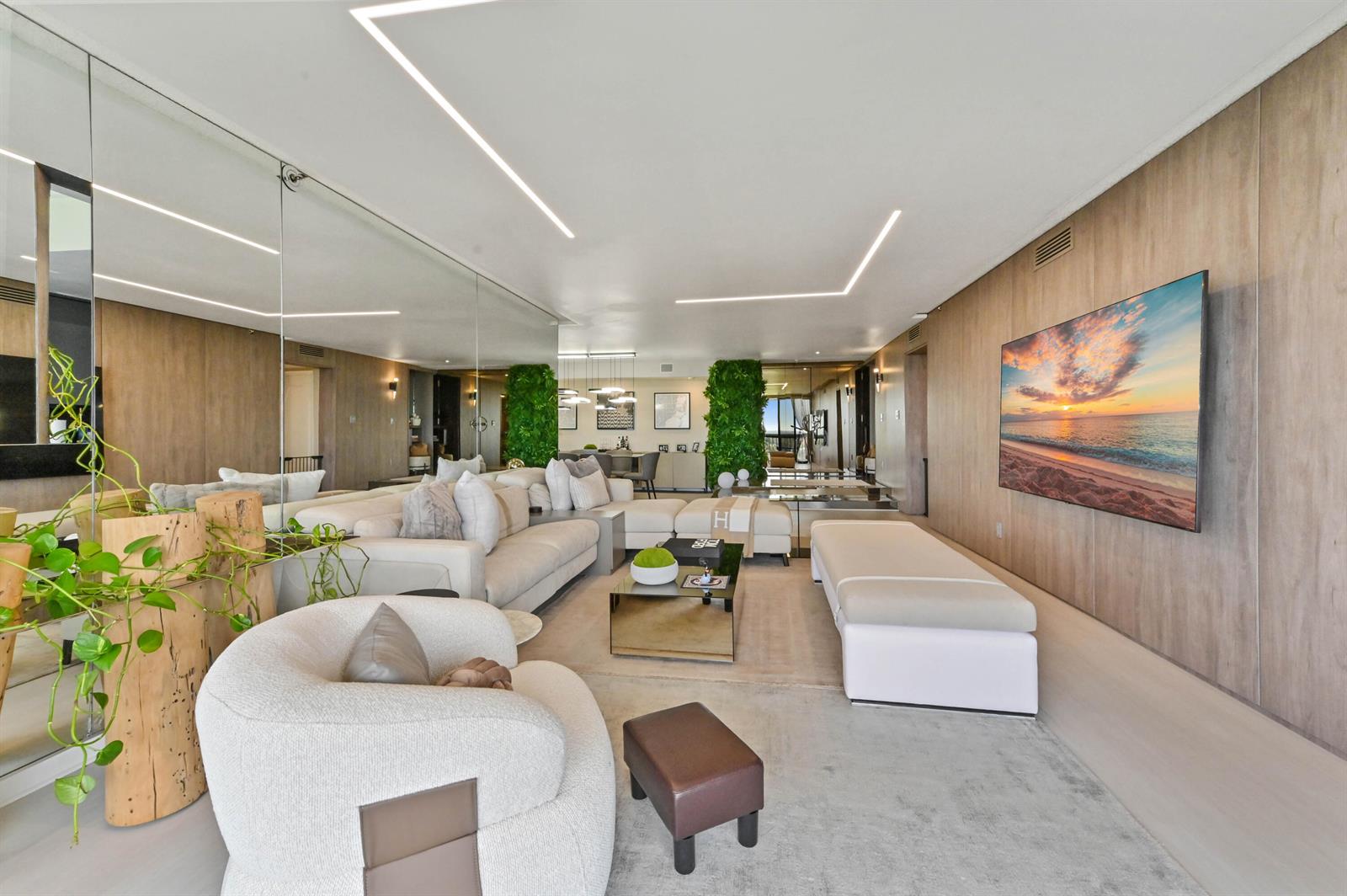 A modern living room features a large sectional sofa, wood-paneled walls, and a wall-mounted television — 1900 Consulate Place # 1205, West Palm Beach FL 33401, WEST PALM BEACH, FL