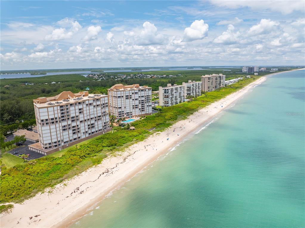 An aerial view shows several tall beachfront condominium buildings along a sandy coastline — 4180 N HIGHWAY A1A UNIT 305B, HUTCHINSON ISLAND, FL