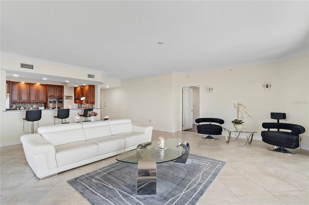 A living room with tile floors, a white sofa, glass coffee tables, and a kitchen — 4180 N HIGHWAY A1A UNIT 305B, HUTCHINSON ISLAND, FL