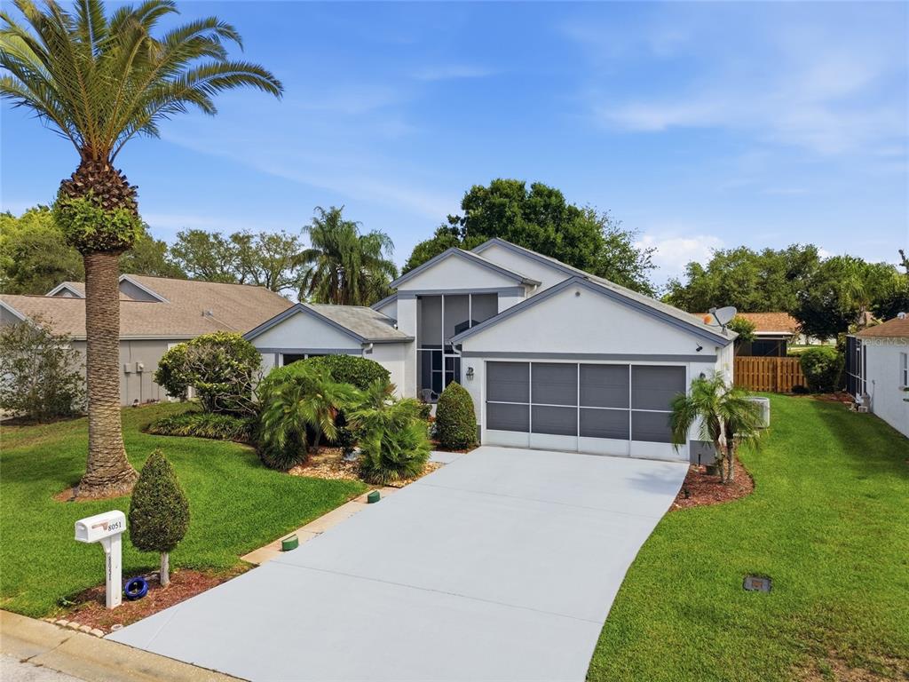 A single-story house with a white exterior, a screened garage, and a palm tree in front — 8051 THATCH TERRACE, HUDSON, FL