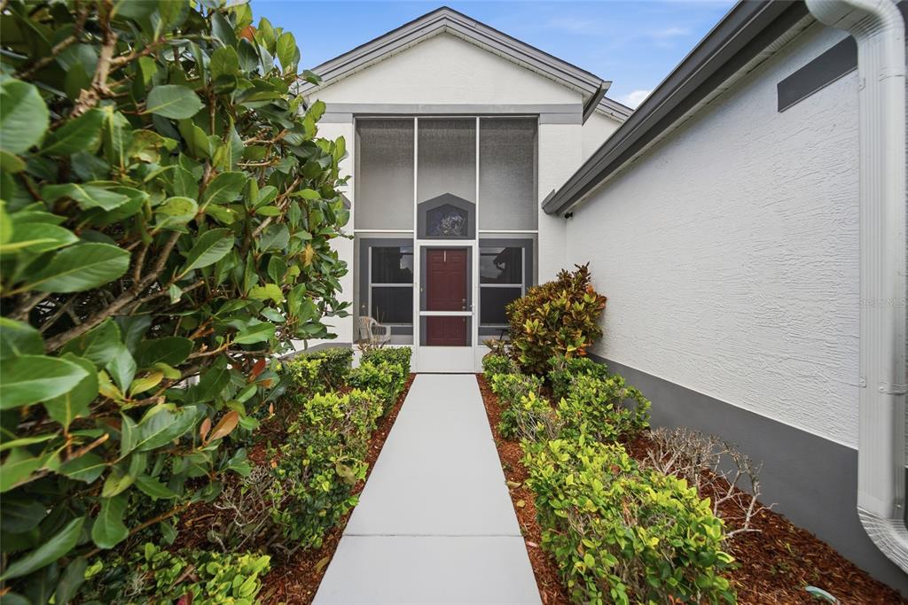A concrete walkway leads to a front entrance enclosed by a screened-in porch — 8051 THATCH TERRACE, HUDSON, FL