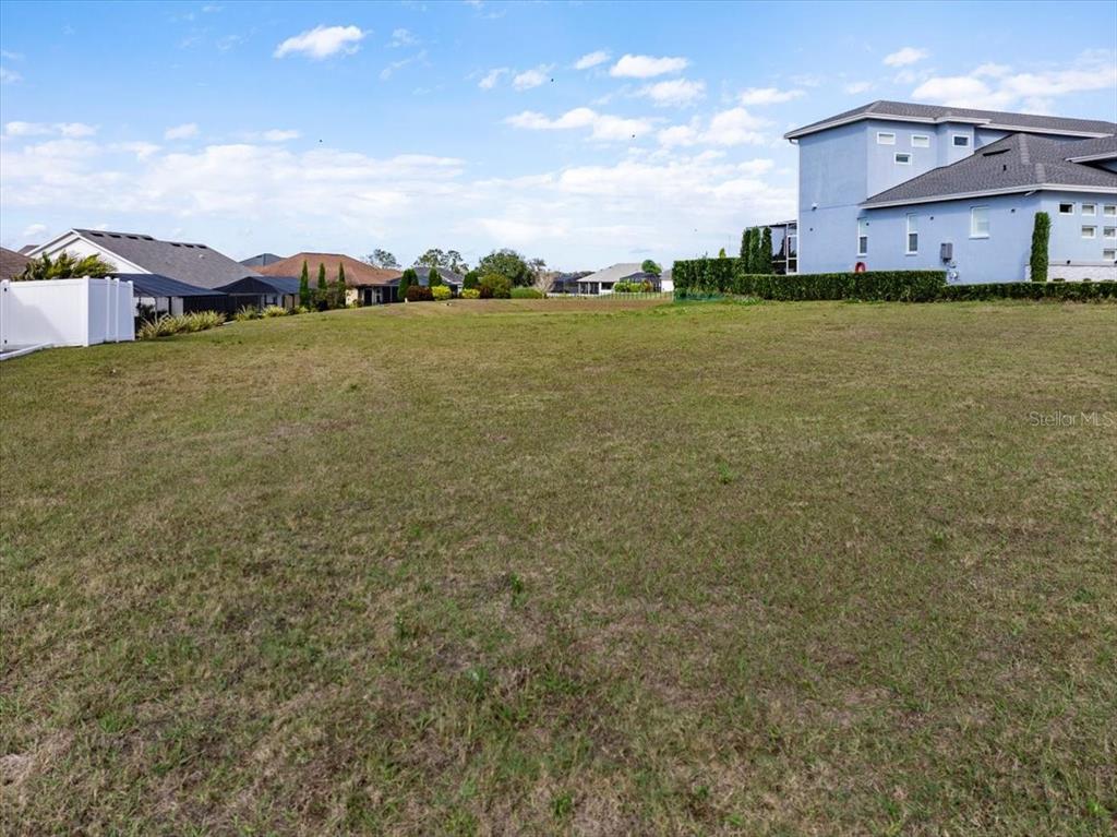 A large, grassy vacant lot is situated in a residential neighborhood with nearby houses — 3334 SHORE DRIVE, LAKELAND, FL