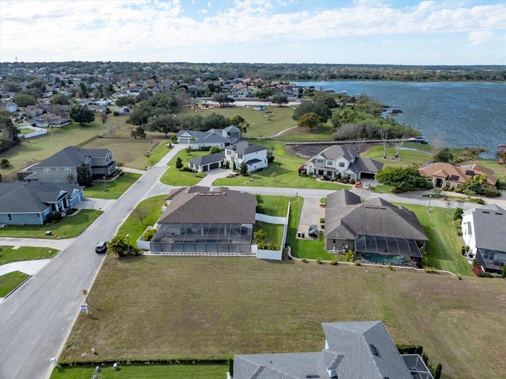 An aerial view shows a residential neighborhood with houses, a large vacant lot, and a lake — 3334 SHORE DRIVE, LAKELAND, FL