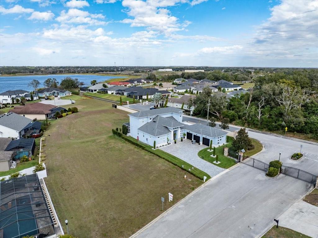 An aerial view shows a modern house with a large yard and gated driveway — 3334 SHORE DRIVE, LAKELAND, FL