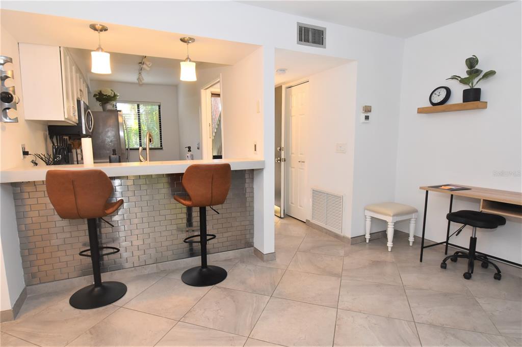 A kitchen with a breakfast bar, two stools, and an adjacent desk area — 1716 GLENHOUSE DRIVE UNIT GL323, SARASOTA, FL