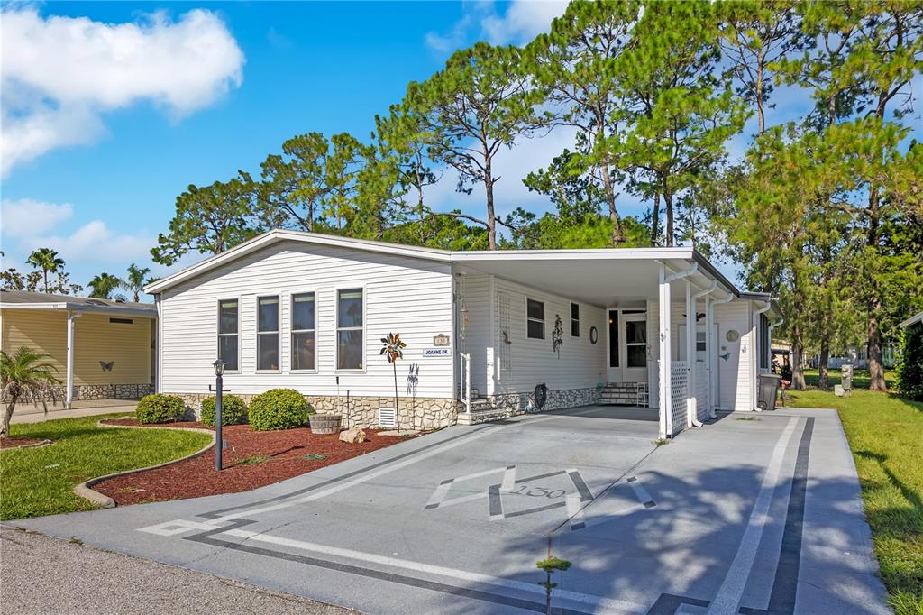 A single-story mobile home with white siding, a carport, and a painted concrete driveway — 130 JOANNE DRIVE, DAVENPORT, FL