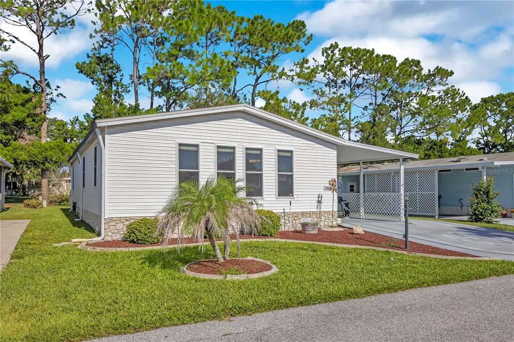 A single-story manufactured home with white siding, a carport, and a small front yard — 130 JOANNE DRIVE, DAVENPORT, FL