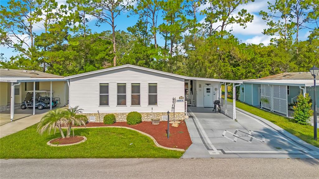 A single-story manufactured home with light siding, a stone base, and an attached carport — 130 JOANNE DRIVE, DAVENPORT, FL
