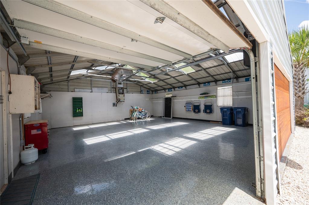 A spacious garage with a gray epoxy floor, white walls, and a large open door — 240 GLADIOLUS STREET, ANNA MARIA, FL