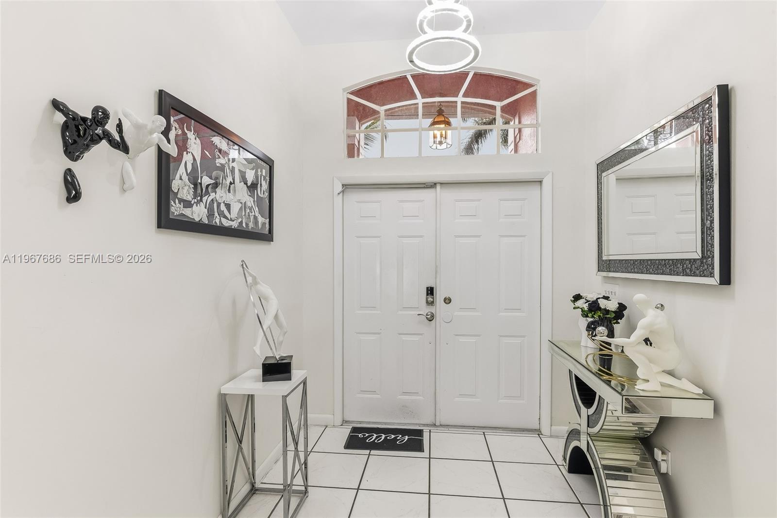 A bright entryway features white tile floors, double doors, and modern decorative wall sculptures — 1203 SE 27th ST, Cape Coral FL 33904, CAPE CORAL, FL
