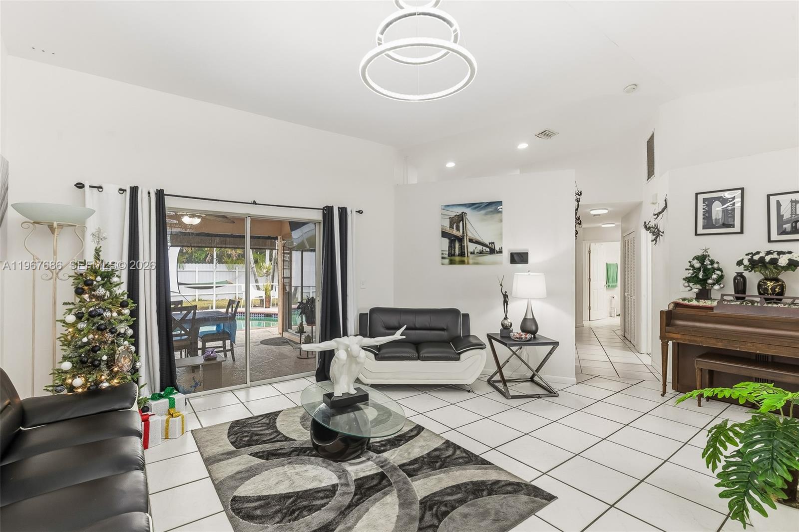A living room features white tile floors, a black and white sofa, and a piano — 1203 SE 27th ST, Cape Coral FL 33904, CAPE CORAL, FL