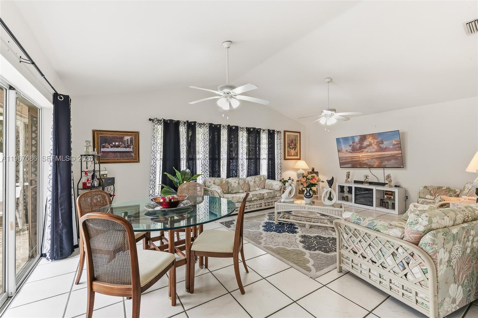 A living and dining area features white tile floors, floral furniture, and two ceiling fans — 1203 SE 27th ST, Cape Coral FL 33904, CAPE CORAL, FL