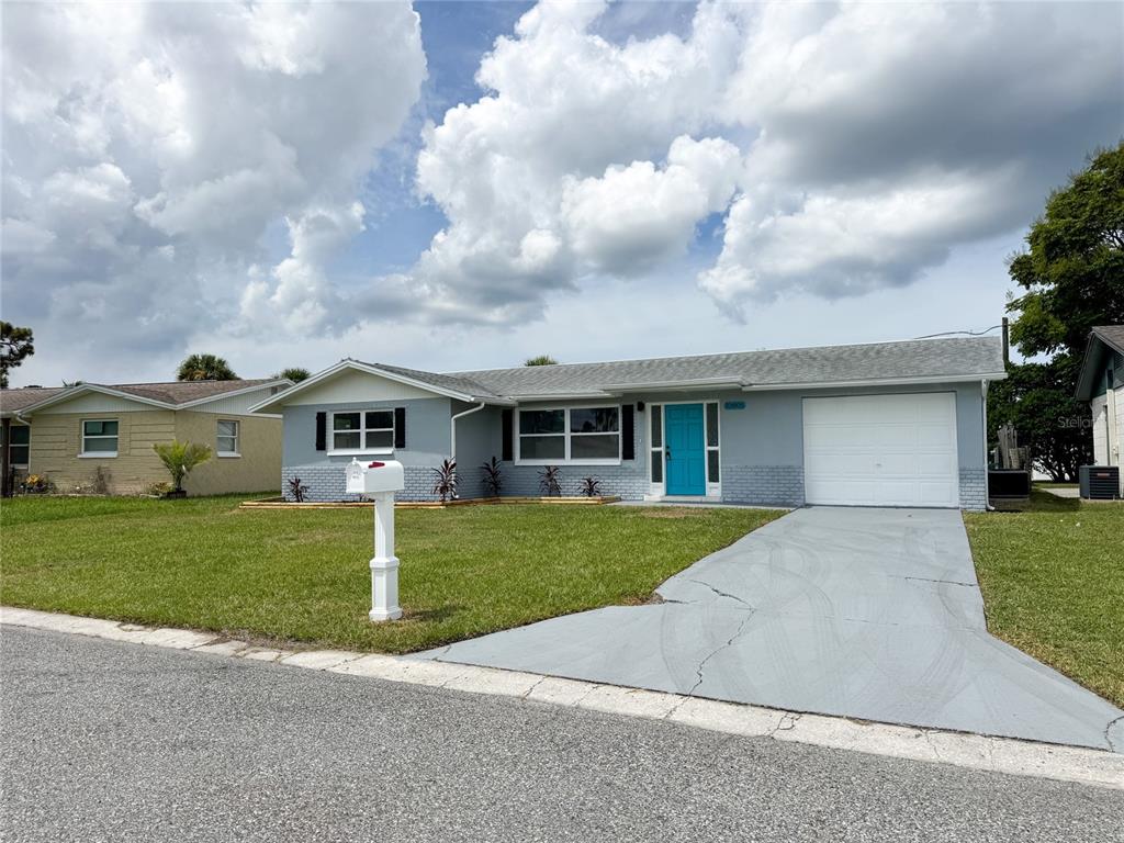 A single-story gray house with a bright blue front door and a concrete driveway — 10805 FILLMORE AVENUE, PORT RICHEY, FL
