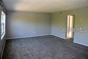 A living room with gray walls, gray carpeting, and a doorway leading to another room — 1000 S SEMORAN BOULEVARD UNIT 408, WINTER PARK, FL