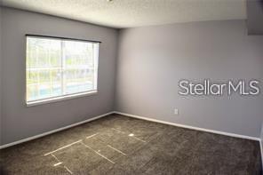 An empty bedroom features gray walls, dark carpeting, and a window with white blinds — 1000 S SEMORAN BOULEVARD UNIT 408, WINTER PARK, FL