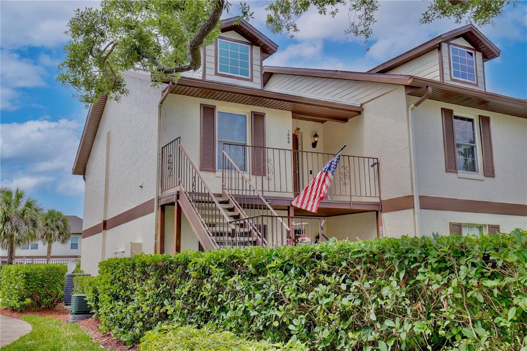 A two-story building exterior features a second-floor balcony with stairs and an American flag — 600 NORTHERN WAY UNIT 1608, WINTER SPRINGS, FL
