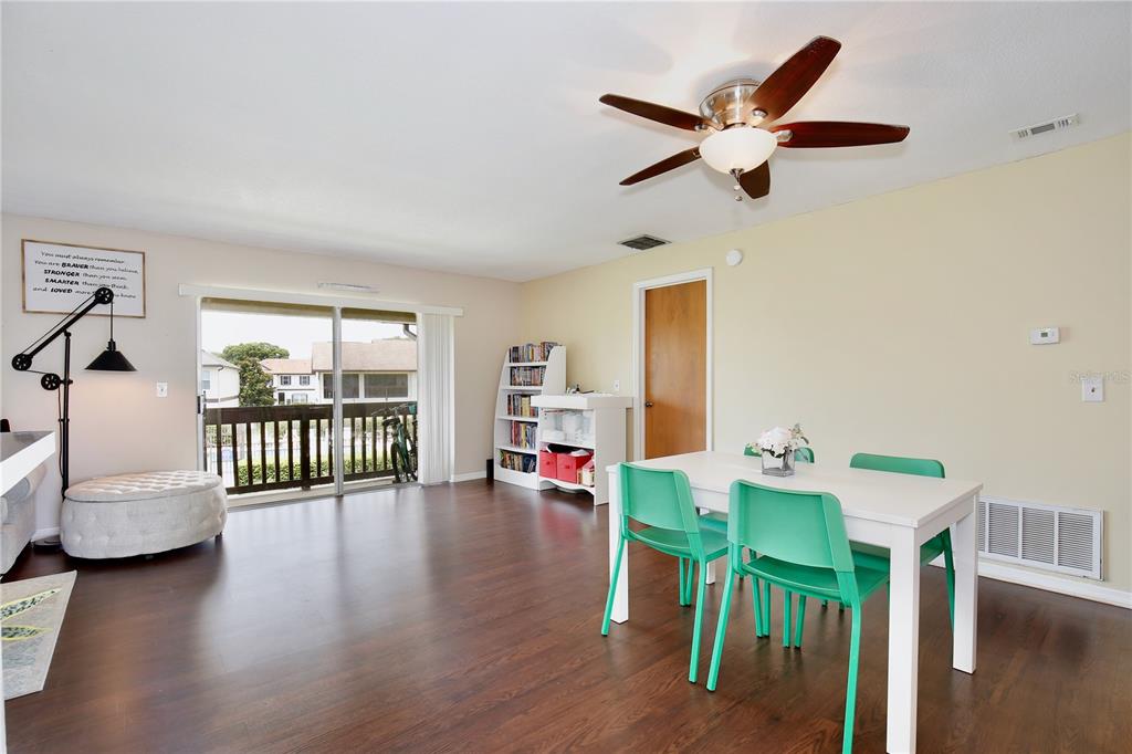A dining area with a white table, green chairs, and a sliding door to a balcony — 600 NORTHERN WAY UNIT 1608, WINTER SPRINGS, FL