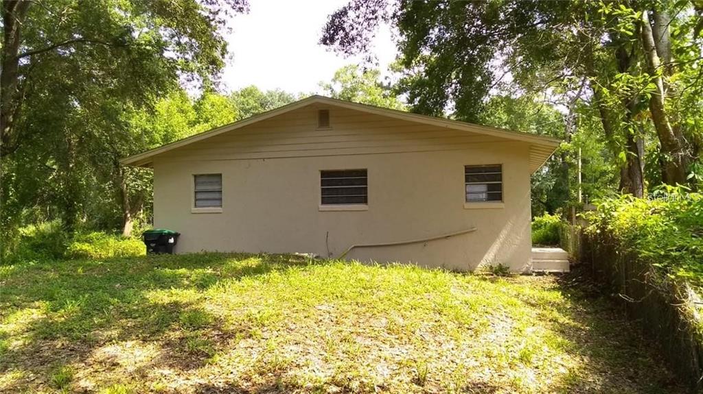 A single-story house with red stucco walls, a white gable, and a dark front porch — 5036 COLLEGE, ORLANDO, FL