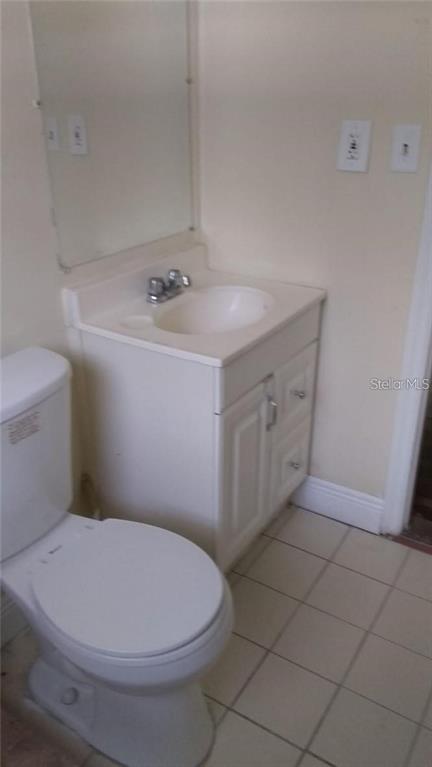 A bathroom features a white toilet, a vanity with a sink, and tiled flooring — 5036 COLLEGE, ORLANDO, FL