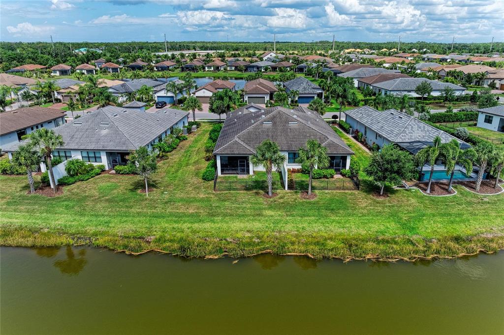 An aerial view shows several suburban houses with tiled roofs situated along a waterfront — 7018 HOLBROOK COVE, BRADENTON, FL