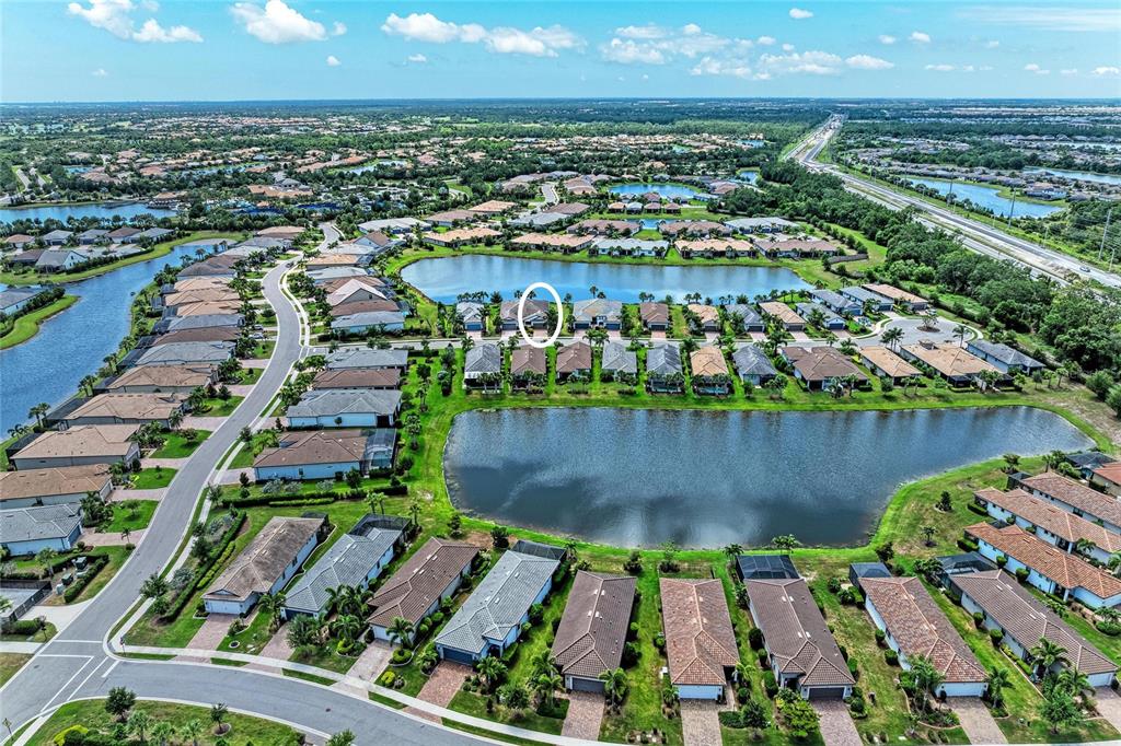 An aerial view shows a suburban neighborhood with houses surrounding several ponds — 7018 HOLBROOK COVE, BRADENTON, FL