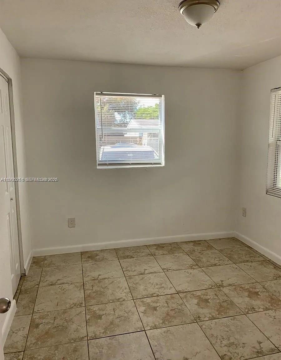 An empty room features white walls, a single window, and light-colored tiled flooring — 1277 NW 58th St, Miami FL 33142, MIAMI, FL