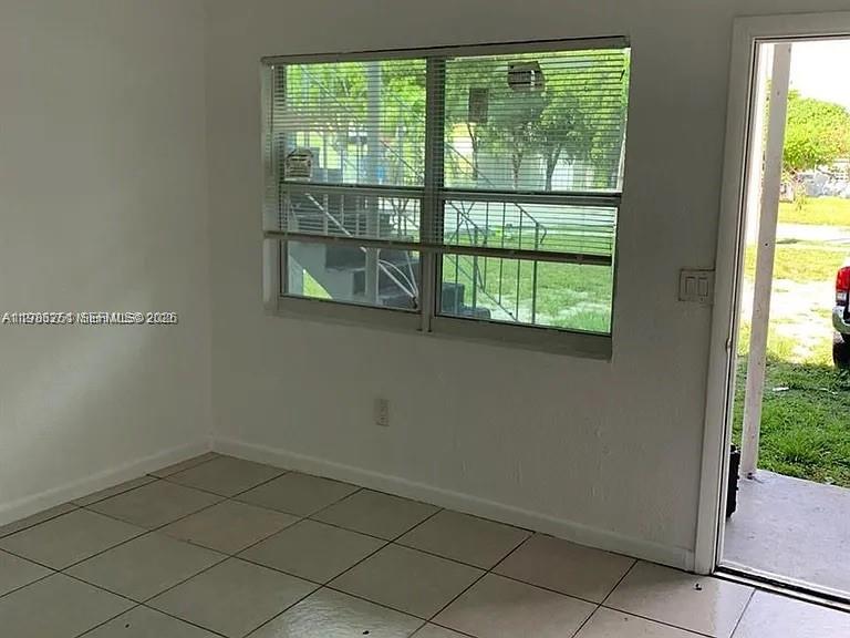 A room with tiled floors, a window with horizontal blinds, and an open doorway — 1277 NW 58th St, Miami FL 33142, MIAMI, FL